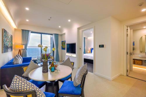 a living room with a blue couch and a table and chairs at Nexus House Ocean front & Hillside Phú Quốc in Phu Quoc