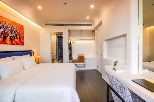 a bedroom with a large white bed and a desk at Nexus House Ocean front & Hillside Phú Quốc in Phu Quoc