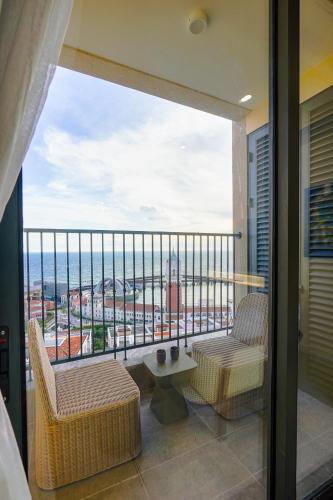 a balcony with two chairs and a view of the ocean at Nexus House Ocean front & Hillside Phú Quốc in Phu Quoc