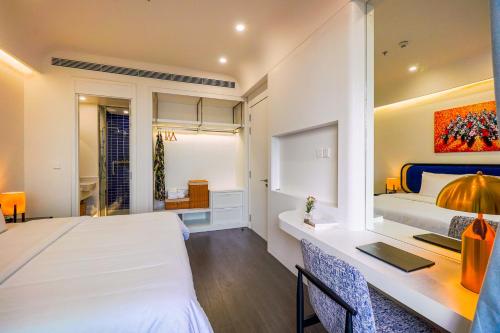 a bedroom with a white bed and a desk with a desk at Nexus House Ocean front & Hillside Phú Quốc in Phu Quoc