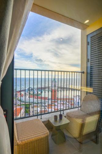 a balcony with two chairs and a view of the ocean at Nexus House Ocean front & Hillside Phú Quốc in Phu Quoc
