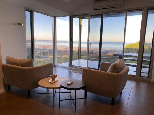 a living room with chairs and tables and large windows at Bayview Retreat - Esplanade home w wifi in Wallaroo