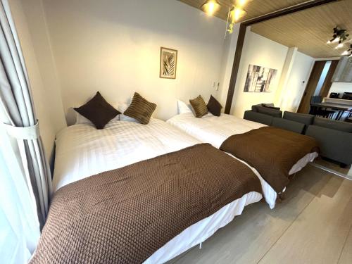 a bedroom with two beds and a couch at Naos House Osaka 4 New Open 一軒家貸切 in Osaka