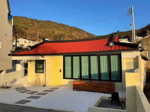a house with a red roof with a hill in the background at Onheim in Tongyeong
