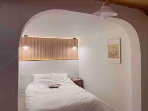 um quarto com uma cama branca e um arco em Onheim em Tongyeong