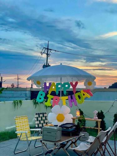 a table with an umbrella and chairs and a table with a party sign at Onheim in Tongyeong
