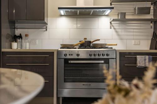 a kitchen with a stove with two pans on it at Azami - Charming Gilbert Cottage in Adelaide