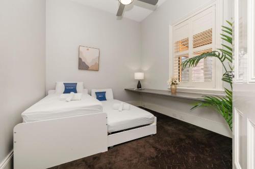 Cette chambre blanche dispose de deux lits et d'une fenêtre. dans l'établissement Azami - Charming Gilbert Cottage, à Adélaïde