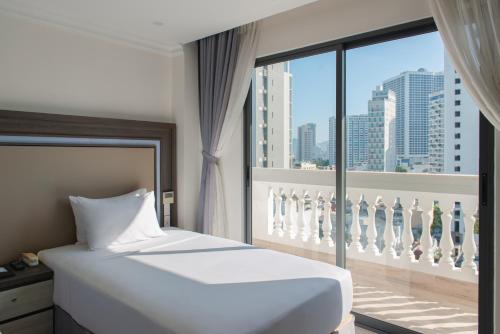 a bedroom with a white bed and a large window at Seven Seas Hotel Nha Trang in Nha Trang