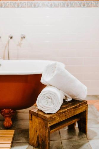 a pile of towels on a stool next to a bath tub at 'Wilpine' Poolside Country Luxury near Town in Mudgee