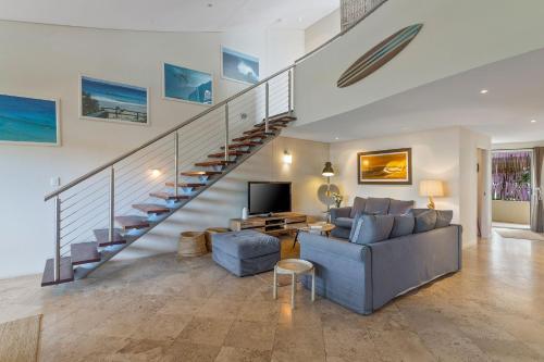 a living room with a couch and a staircase at Jades on Lawson 2 in Byron Bay