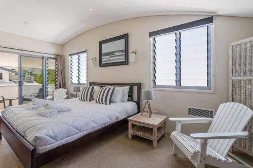 a bedroom with a large bed and two white chairs at Jades on Lawson 2 in Byron Bay
