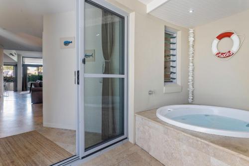 uma casa de banho com uma banheira e uma porta de vidro em Jades on Lawson 2 em Byron Bay