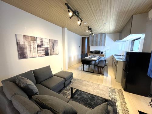 a living room with a couch and a kitchen with a table at Naos House Osaka 4 New Open 一軒家貸切 in Osaka