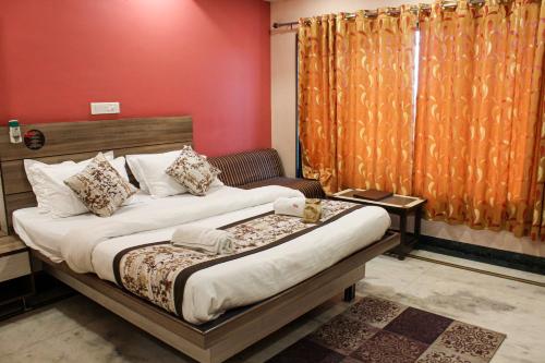 a bedroom with a bed and a red wall at Hotel Gujrat in Nagpur