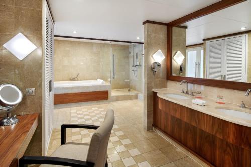 a bathroom with two sinks and a bath tub and a chair at Le Méridien Nouméa Resort & Spa in Noumea