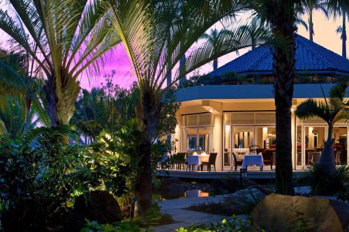 a house with palm trees in front of it at Le Méridien Nouméa Resort & Spa in Noumea