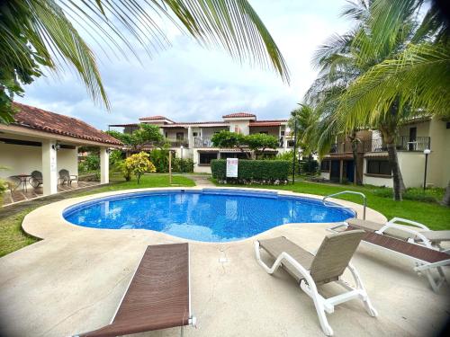 a swimming pool with two chairs and a house at The Beach House Ground Floor Condo in Coco
