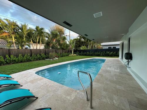a swimming pool with chairs in a backyard at The Sun House - 3 Bed, 2 Bath, Private Pool, Fire Pit, Huge Backyard in Fort Lauderdale
