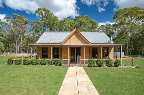 a house with a metal roof on a yard at Caballo Retreat Cottage in Bargo