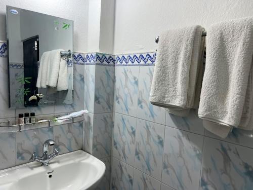uma casa de banho com lavatório, espelho e toalhas em Ama Garden Sauraha em Sauraha
