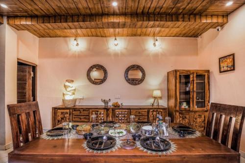 uma sala de jantar com mesa, cadeiras e espelhos em SaffronStays Zephyr em Nainital