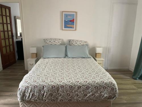 a bedroom with a bed with a comforter and two lamps at La mission in Saint-Martin-des-Noyers