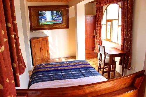 1 dormitorio con cama, mesa y ventana en Súmaq Puñuy, en Yungay