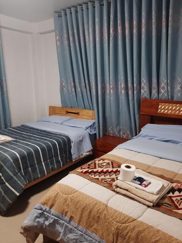 1 dormitorio con 2 camas y cortinas azules en Súmaq Puñuy, en Yungay