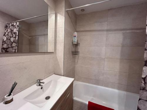 y baño con lavabo y bañera con espejo. en Piso Castelló d'Empúries en Castellón de Ampurias