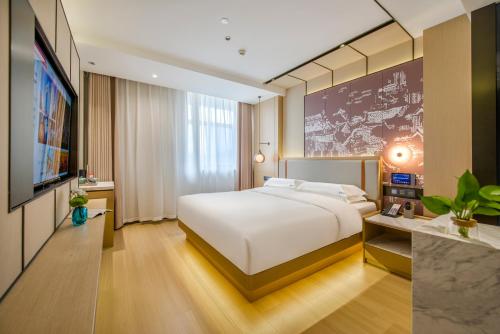 ein Schlafzimmer mit einem großen weißen Bett und einem TV in der Unterkunft Yiwu Baide Theme Hotel in Yiwu