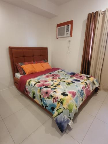 a bed with a colorful comforter on it in a bedroom at Spacious Minimalist Studio at Matina Enclaves in Davao City