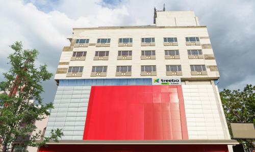 a tall white building with a red facade at Treebo Trend D Grand in Madurai