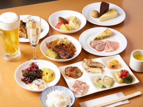 a table with plates of food and a glass of beer at 箱根湯本ホテル in Hakone