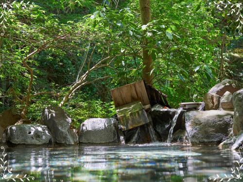 a wooden bench sitting next to a stream of water at 箱根湯本ホテル in Hakone