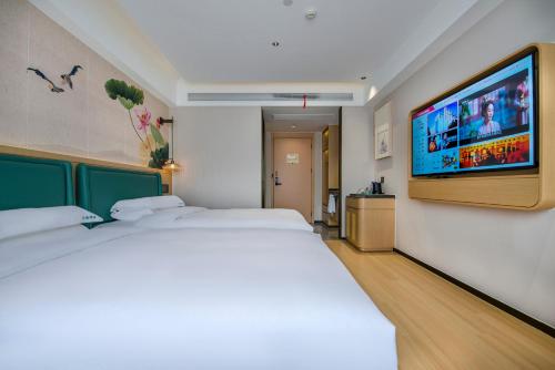 a hotel room with two beds and a flat screen tv at Yiwu Baide Theme Hotel in Yiwu