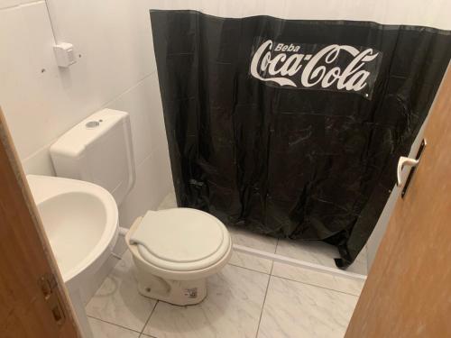 a bathroom with a cocacola shower curtain and a toilet at Loft Coca-Cola Passo Fundo in Passo Fundo