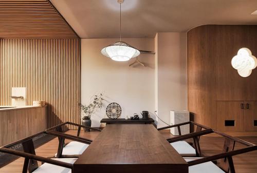 a dining room with a wooden table and a light fixture at Gyeongju Denbasta Ryokan in Gyeongju