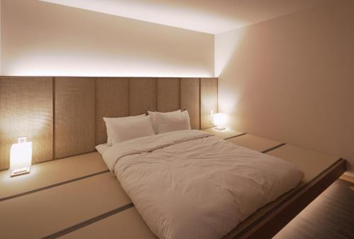 a bedroom with a white bed with two lights at Gyeongju Denbasta Ryokan in Gyeongju