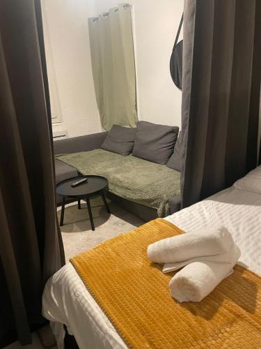 una habitación con 2 toallas en una cama y un sofá en Studio du Vercors, en Fontaine