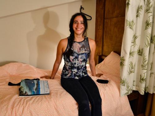 a woman sitting on a bed with a book at R Guest House in Osaka
