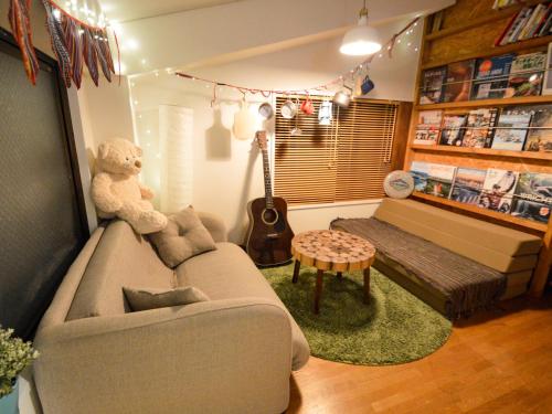 a living room with a teddy bear sitting on a couch at R Guest House in Osaka