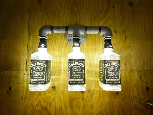 three bottles of alcohol are attached to a pipe at R Guest House in Osaka