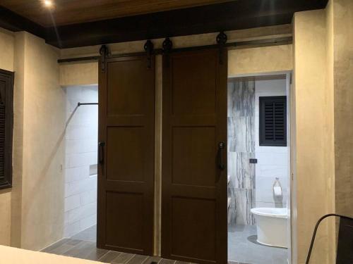 a bathroom with a wooden door and a toilet at Spacious Beachfront Unit at Canyon Cove Nasugbu in Nasugbu