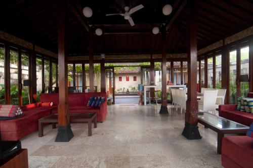 a pavilion with red couches and tables and windows at Villa Alcheringa Yogyakarta in Yogyakarta