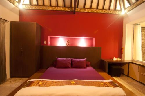 a bedroom with a bed with a red wall at Villa Alcheringa Yogyakarta in Yogyakarta