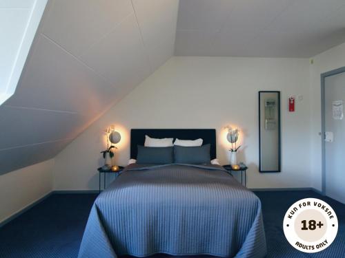a bedroom with a bed with blue sheets and two lamps at Ærø Hotel - Adults only in Marstal