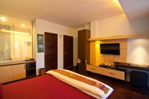 a bedroom with a large bed and a flat screen tv at Villa Alcheringa Yogyakarta in Yogyakarta