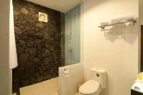 a bathroom with a toilet and a stone wall at Villa Alcheringa Yogyakarta in Yogyakarta