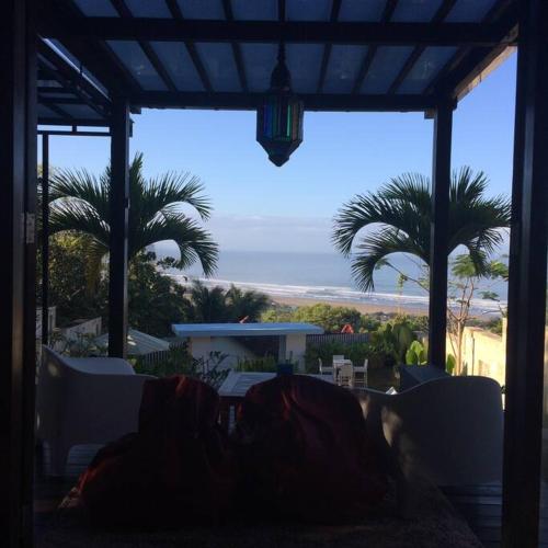 a patio with palm trees and a view of the ocean at Villa Alcheringa Yogyakarta in Yogyakarta